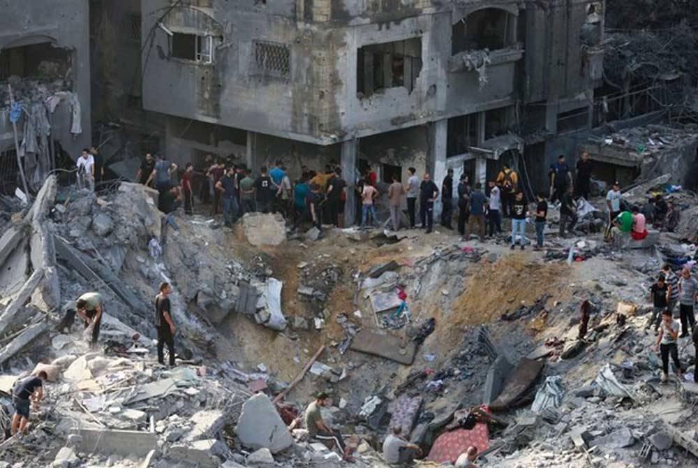 Rakyat Palestin meneliti kesan serangan Israel pada malam sebelumnya di kem pelarian Jabalia di Semenanjung Gaza. - Foto: AFP