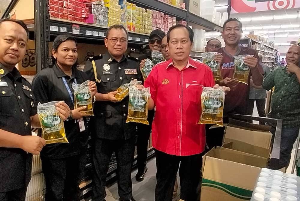 Ahmad ( kanan) menunjukkan bekalan minyak paket bersubsidi ketika melakukan tinjauan di sebuah pasar raya di daerah ini pada Ahad.