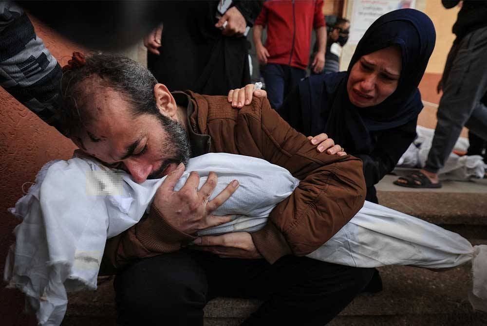 Jamil Al-Agha dan isterinya menangisi kematian salah seorang daripada dua anak pasangan itu yang terbunuh dalam pengeboman Israel, di Khan Yunis pada Ahad, di tengah-tengah pertempuran berterusan antara Israel dan pejuang Hamas. - Foto AFP