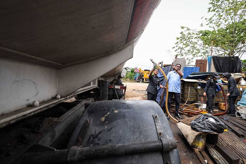 Jegan (dua dari kiri) bersama pegawainya menunjukkan lori tanker diisi sebahagian daripada 28,000 liter minyak diesel tanpa permit yang telah disita dalam Ops Tiris di sebuah stor dekat Permatang Pauh, pada Isnin. - Foto Bernama