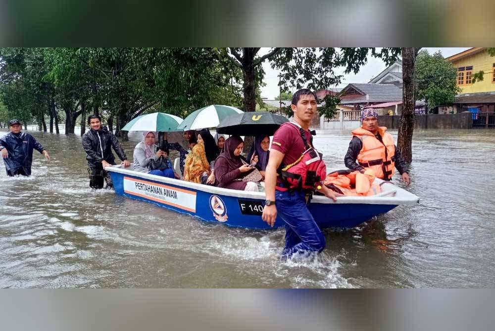 Anggota penyelamat membantu memindahkan penduduk yang terjejas banjir. - Foto Angkatan Pertahanan Awam Malaysia (APM)