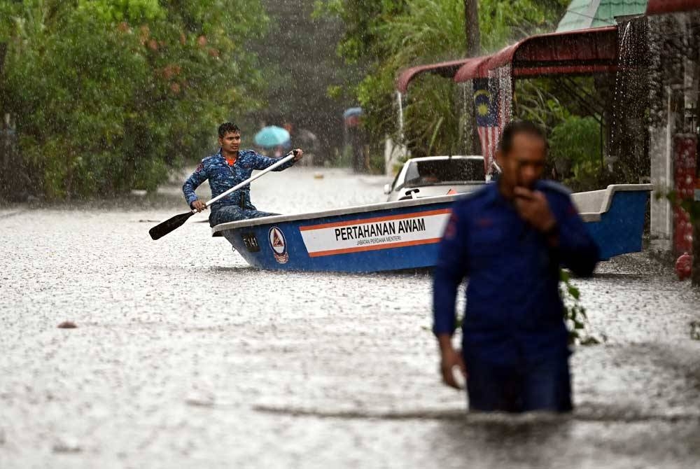 Pasukan penyelamat melakukan pemantauan di kawasan perumahan yang dinaiki air ketika tinjauan di Taman Murni Permai, Tok Jembal. - Foto Bernama