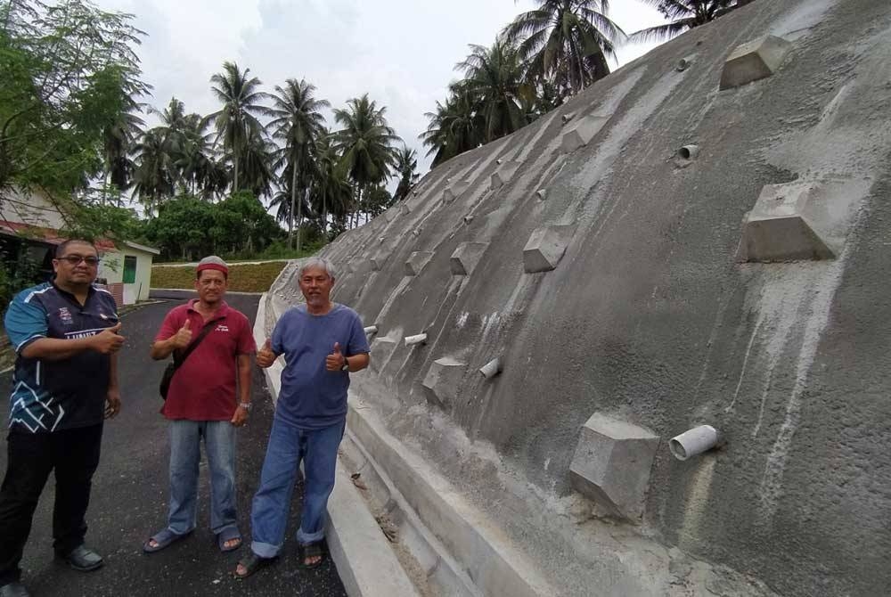 Abd Rashid (kanan) dan Noor Hisham (kiri) menunjukkan tebing yang telah dibaik pulih oleh MPM dan syarikat konsesi di Taman Sri Batik di sini.