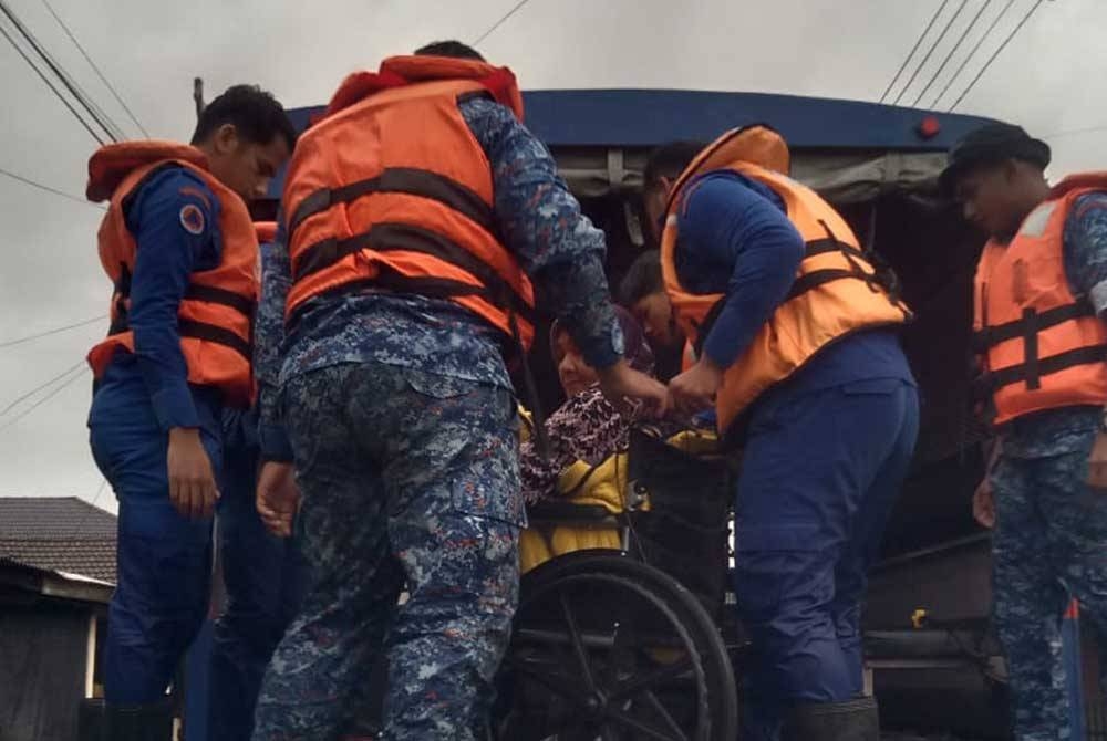 Anggota APM membantu memindahkan penduduk yang terjejas banjir. - Foto APM