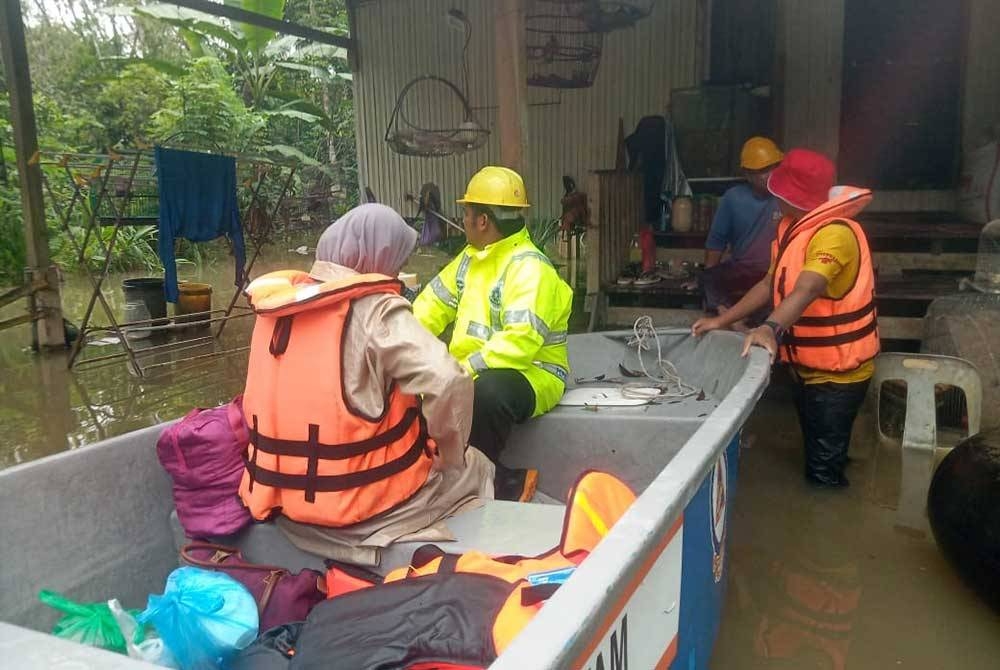 Anggota Angkatan Pertahanan Awam Malaysia (APM) memindahkan mangsa banjir yang terkandas di Kampung Tasek Tok Kundur, mukim Bukit Awang. - Foto APM