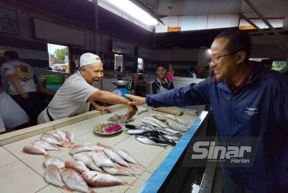 Ahmad Samsuri (kanan) beramah mesra dengan peniaga di Pasar Binjai, Chukai pada Selasa.