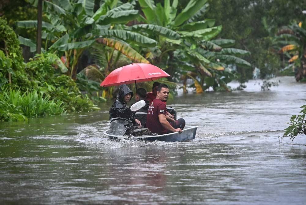 Sebahagian penduduk meredah banjir dengan menaiki bot untuk ke tempat yang lebih selamat selepas kawasan berkenaan dinaiki air. - Foto Bernama.