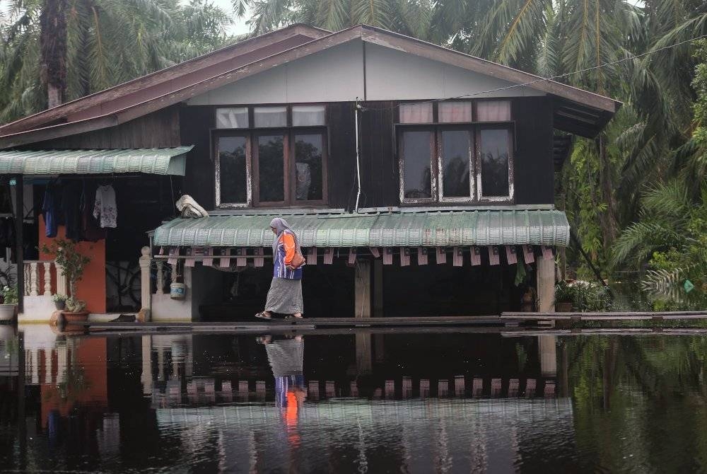 Mangsa banjir meniti titi di halaman rumahnya berikutan banjir yang berlaku ketika tinjauan di Matang Pasir Changkat Lobak pada 11 November lalu. - Foto Bernama