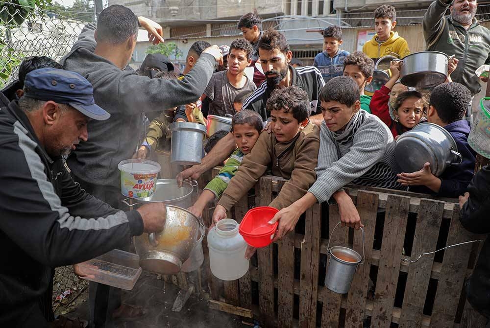 Orang ramai menerima bantuan makanan di bandar Rafah, selatan Semenanjung Gaza pada Ahad. - Foto Xinhua