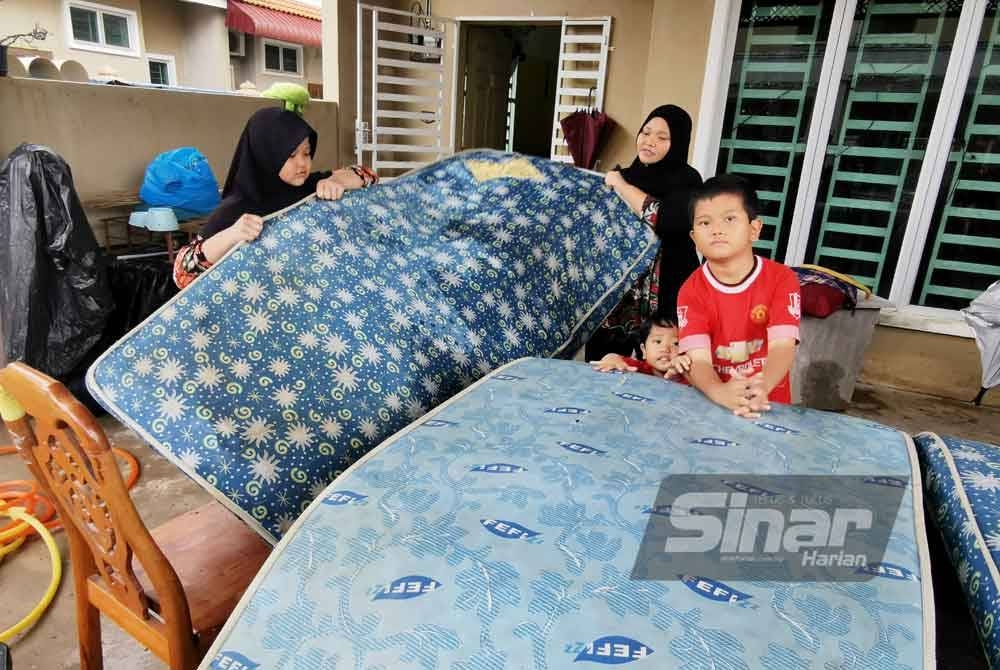 Nor Aidawaty bersama anak-anaknya membersihkan rumah mereka di Taman Desa YT yang dinaiki air ketika banjir melanda pada Isnin lalu.