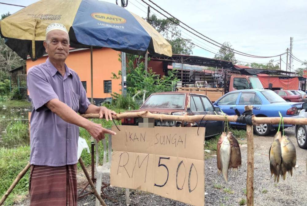 Omar menunjukkan harga ikan tembakan RM5 seikat