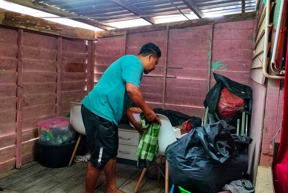 Mohd Farid bersama barangan yang telah dibungkus dan disimpan sebagai persediaan hadapi banjir.