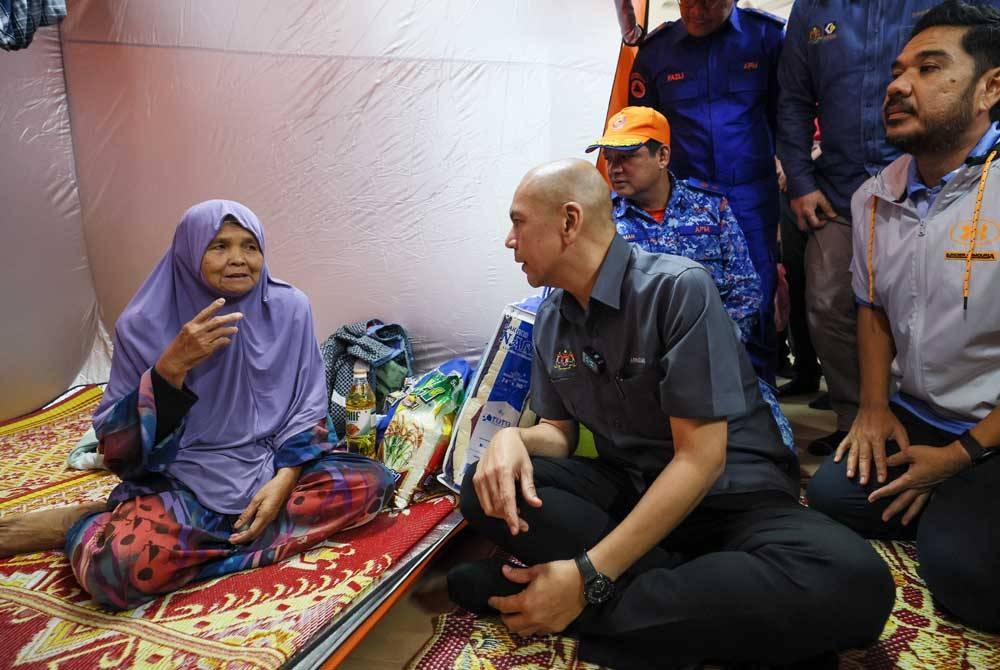 Armizan (dua dari kiri) menyantuni warga emas, Lamoh Abdullah, 67, yang terlibat dalam banjir semasa melawat mereka di PPS SK Atas Tol hari ini. - Foto Bernama