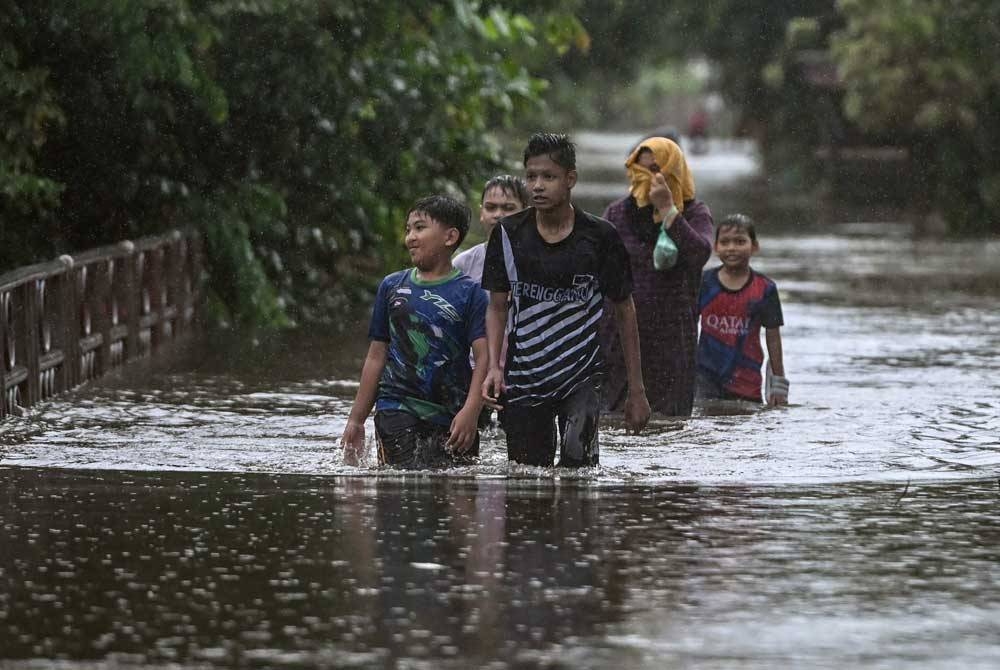 Penduduk meredah banjir untuk pulang ke rumah bagi melihat keadaan rumahnya selepas kawasan berkenaan dinaiki air ketika tinjauan di Kampung Gong Tok Nasek, Kuala Terengganu pada Rabu. - Foto Bernama