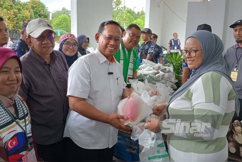 Suhaizan (tiga dari kiri) menyampaikan sumbangan makanan daripada Pasaraya Econsave kepada penduduk di PPR Melana Indah 2, Johor Bahru, pada Sabtu.