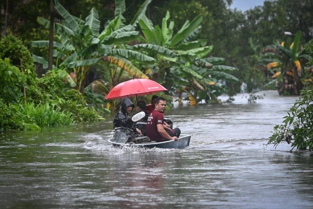 Sebahagian penduduk meredah banjir dengan menaiki bot untuk ke tempat yang lebih selamat selepas kawasan berkenaan dinaiki air. - Foto Bernama