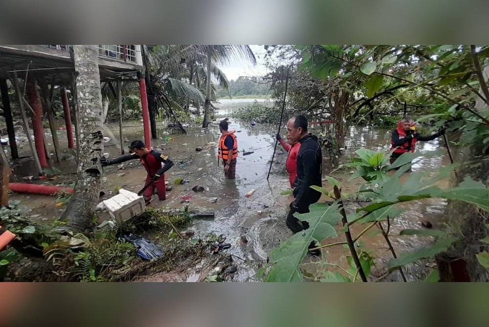 Anggota PPDA melakukan pencarian mangsa yang tergelincir ke dalam sungai di belakang rumahnya di Kampung Kenari pada Ahad.