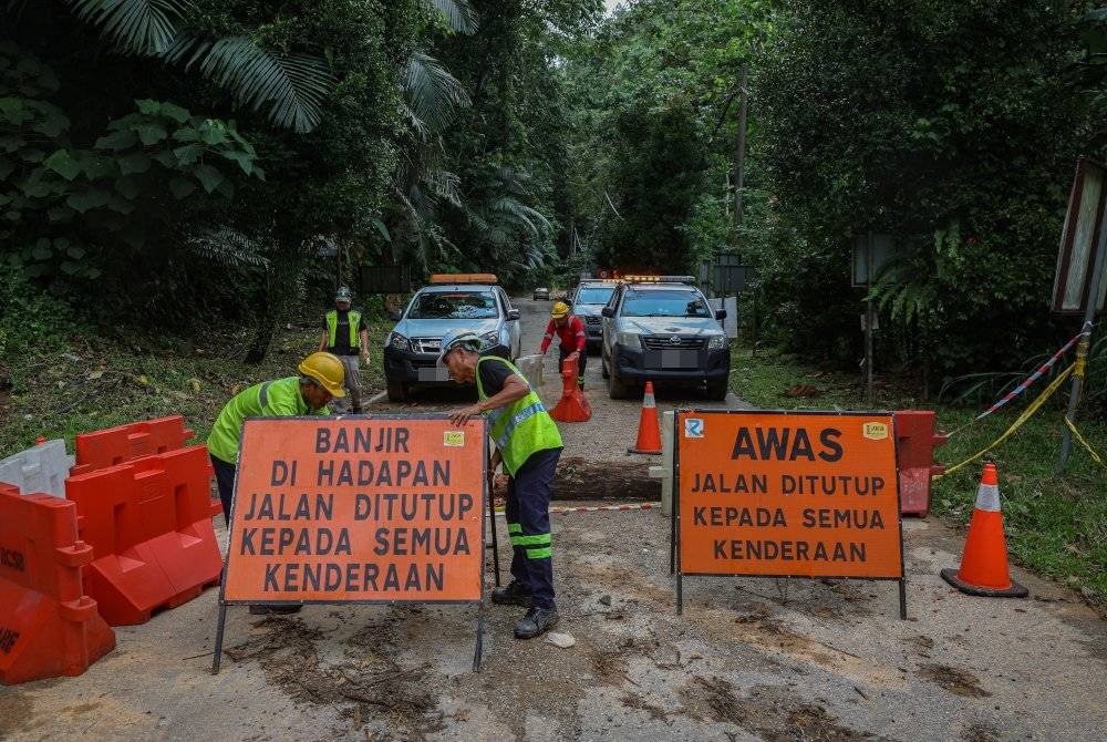 Kakitangan Roadcare menutup Jalan Genting Sempah yang rosak akibat kejadian banjir puing yang berlaku malam semalam. - Foto Bernama