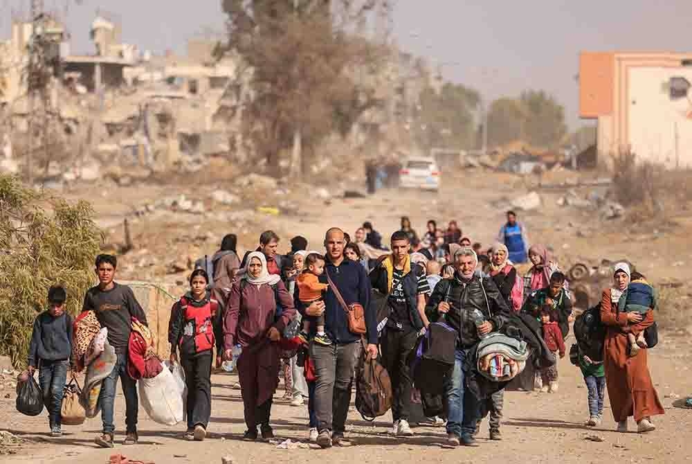 Penduduk Palestin berjalan kaki di sepanjang jalan Salaheddine di daerah Zeitoun di pinggir selatan Gaza City pada Ahad. - Foto AFP