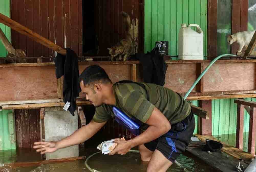 Wan Muhd Jeffri memberi makanan kepada kucing peliharaannya yang kelaparan ketika tinjauan pada Isnin. - Foto: Bernama