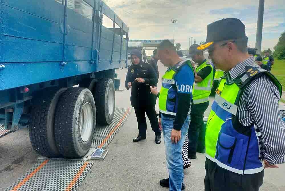 Azrin (kanan) melihat sebuah lori menjalani ujian timbangan berat semasa Ops Patuh Bersepadu JPJ dan JSPT di Plaza Tol Bandar Gamuda Cove pada Selasa.