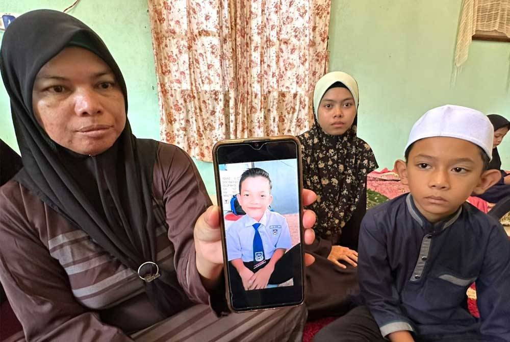 Azlina (kiri) bersama Ahmad Afiq Aiman (kanan) menunjukkan gambar Mohamad Riskie Asraf.