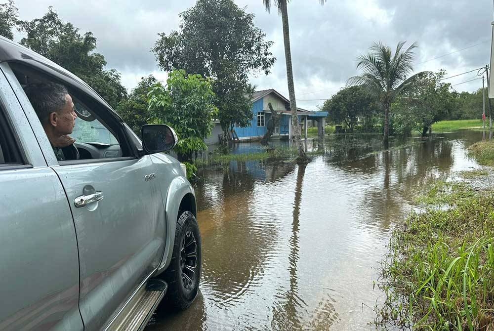 Che Hashim melalui jalan yang digenangi air.