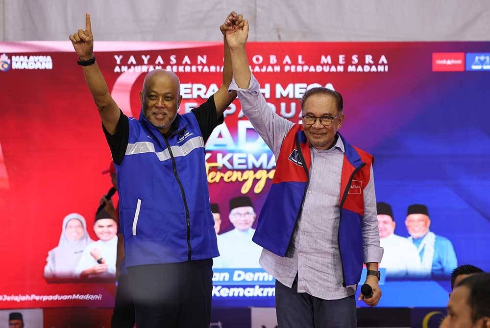 Anwar (kanan) mengangkat tangan calon Barisan Nasional bagi Parlimen Kemaman Jeneral (B) Tan Sri Raja Mohamed Affandi Raja Mohamed Noor semasa hadir pada Ceramah Mega Perpaduan Madani Pilihan Raya Kecil (PRK) Kemaman di Geliga pada malam Rabu. - Foto Bernama