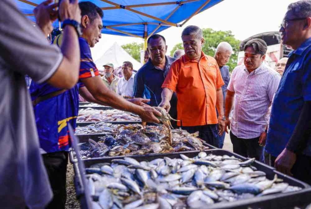 Mohamad (tiga dari kanan) melawat ke Tapak Jualan Agro Madani berhampiran Kompleks Perikanan LKIM sempena Program Santai Madani Bersama Nelayan hari ini. - Foto Bernama