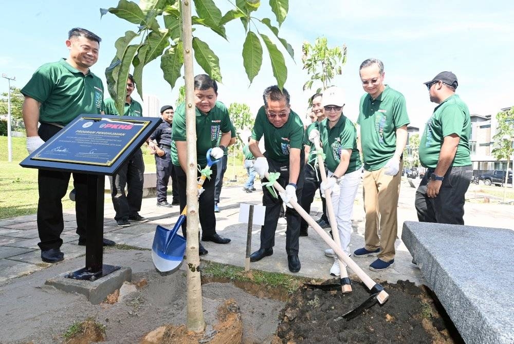 Md Kamarzan (tiga dari kiri) dan Michel menanam pokok selepas selesai acara perasmian.