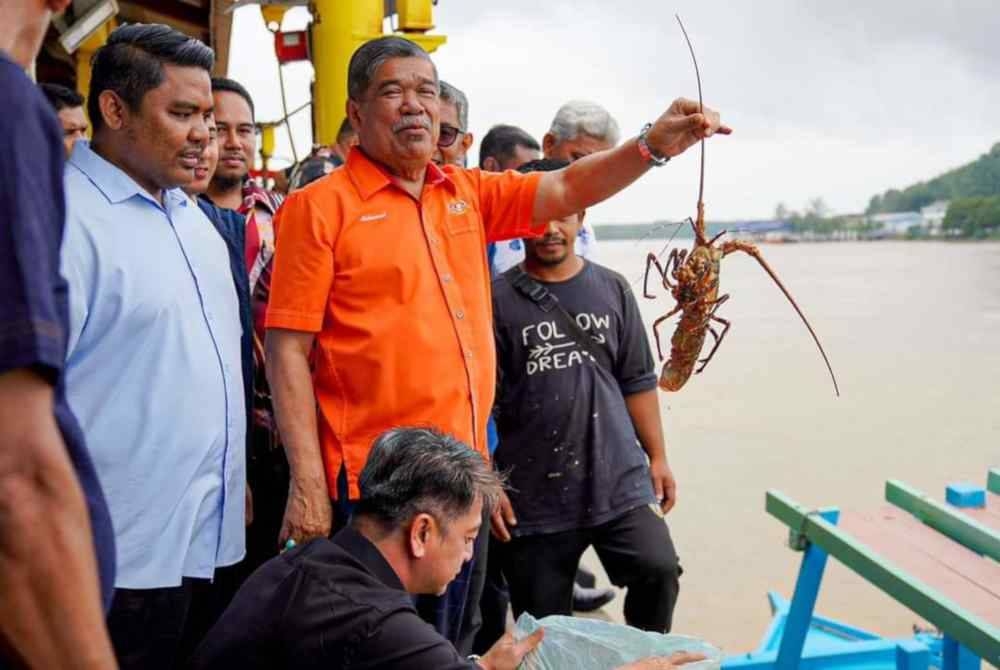 Mohamad (kanan) menunjukkan antara hasil tangkapan nelayan di Kompleks LKIM Kuala Kemaman pada Khamis. (Foto: FB Mohamad Sabu)