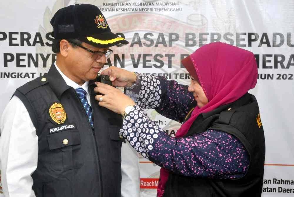 Dr Kasemani memakaikan kamera badan pada vest salah seorang pegawai penguatkuasa Pejabat Kesihatan Daerah Jabatan Kesihatan Negeri Terengganu (JKNT) pada Penyerahan Vest Berkamera peringkat JKNT tahun 2023 di Klinik Kesihatan Rahmat hari ini. - Foto Bernama