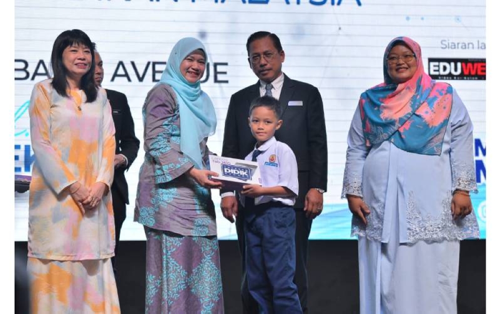 Fadhlina (dia dari kiri) menyerahkan tablet sumbangan Yayasan Didik Negara kepada seorang murid sekolah sambil disaksikan Timbalan Menteri Pendidikan, Lim Hui Ying (kiri) bersempena Majlis Peluncuran Dasar Pendidikan Digital di Pusat Konvensyen Bangi Avenue pada Selasa.