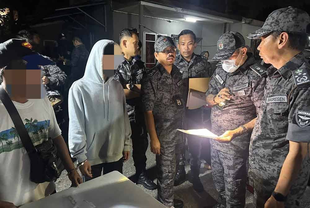 Jafri (kanan) bersama pegawainya melakukan pemeriksaan dokumen warga asing yang ditahan dalam operasi di Kampung Pantai Dalam, Kuala Lumpur pada Sabtu.