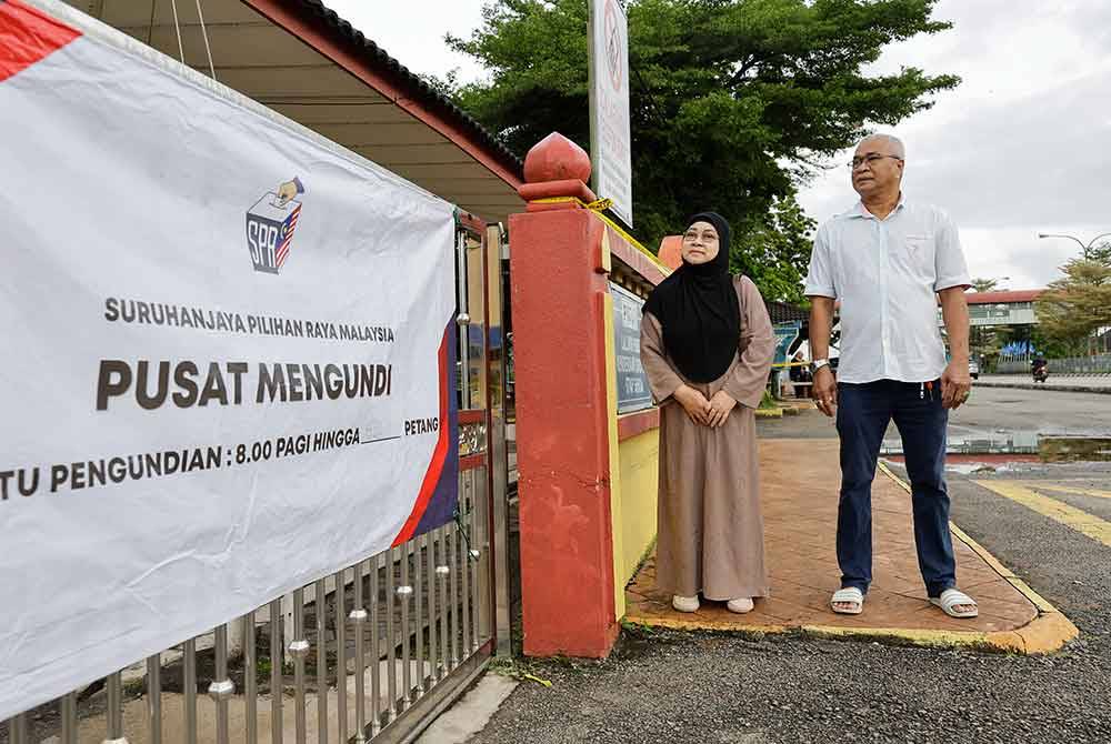 Pasangan suami isteri, Kasmani Che Mat, 61, (kiri) dan suaminya, Omar Muhamad Hussin, 66, beratur di luar Pusat Mengundi Sekolah Menengah Kebangsaan Sultan Ismail untuk mengundi pada Pilihan Raya Kecil (PRK) Parlimen P040 Kemaman hari ini. - Foto Bernama