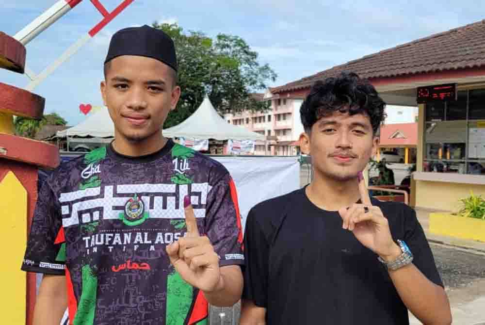 Ahmad Syarif Afham (kanan) dan Mohd Imanuddin antara anak muda yang menunaikan tanggungjawab mengundi di Sekolah Menengah Kebangsaan Sultan Ismail, Chukai pada Sabtu.