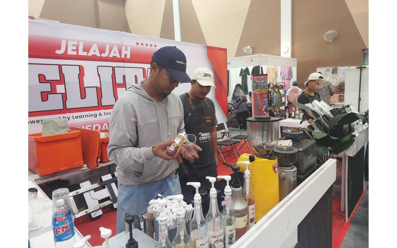 Pemilik Hogeh Coffee, Azroy Hassan Lim (kiri) sedang menyiapkan kopi yang dipesan pelanggan di karnival Jelajah Jelita@RISDA, di Kemaman, kelmarin.