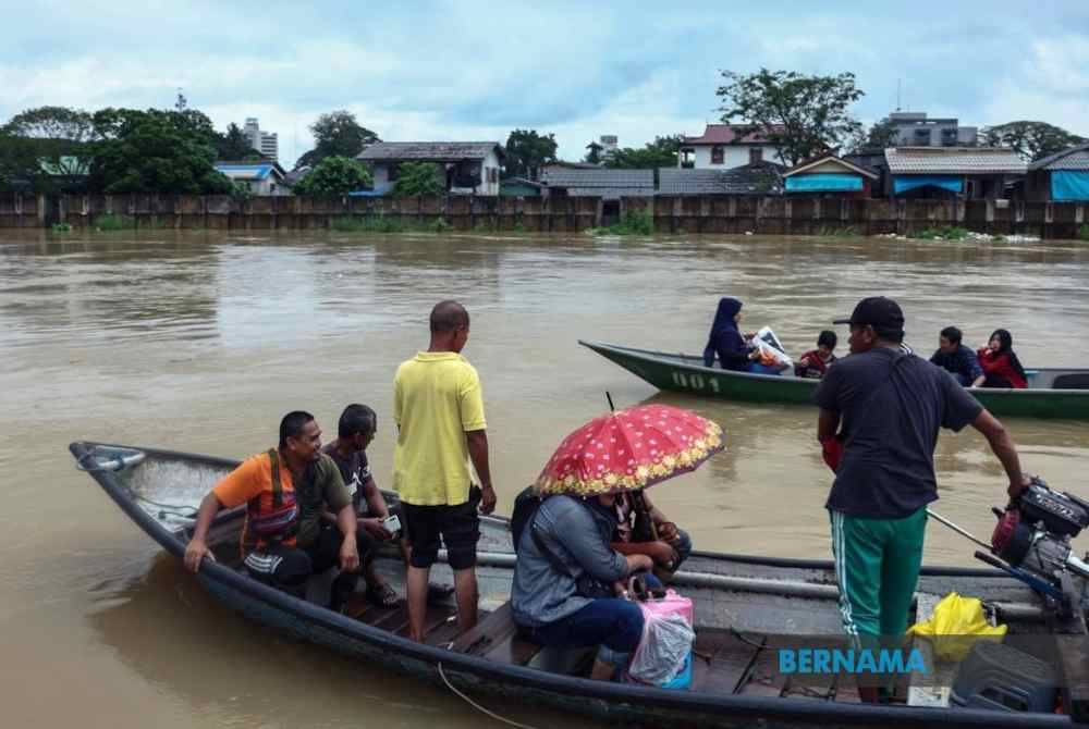 Peniaga masih meneruskan aktiviti perniagaan di Pekan Rantau Panjang walau dilanda banjir. - Foto Bernama