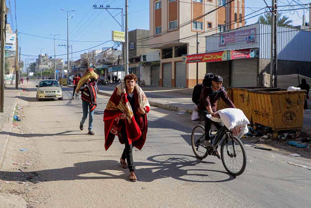 Orang ramai meninggalkan rumah mereka selepas menerima arahan pemindahan dari Israel di bandar Khan Yunis, selatan Semenanjung Gaza. - Foto Xinhua