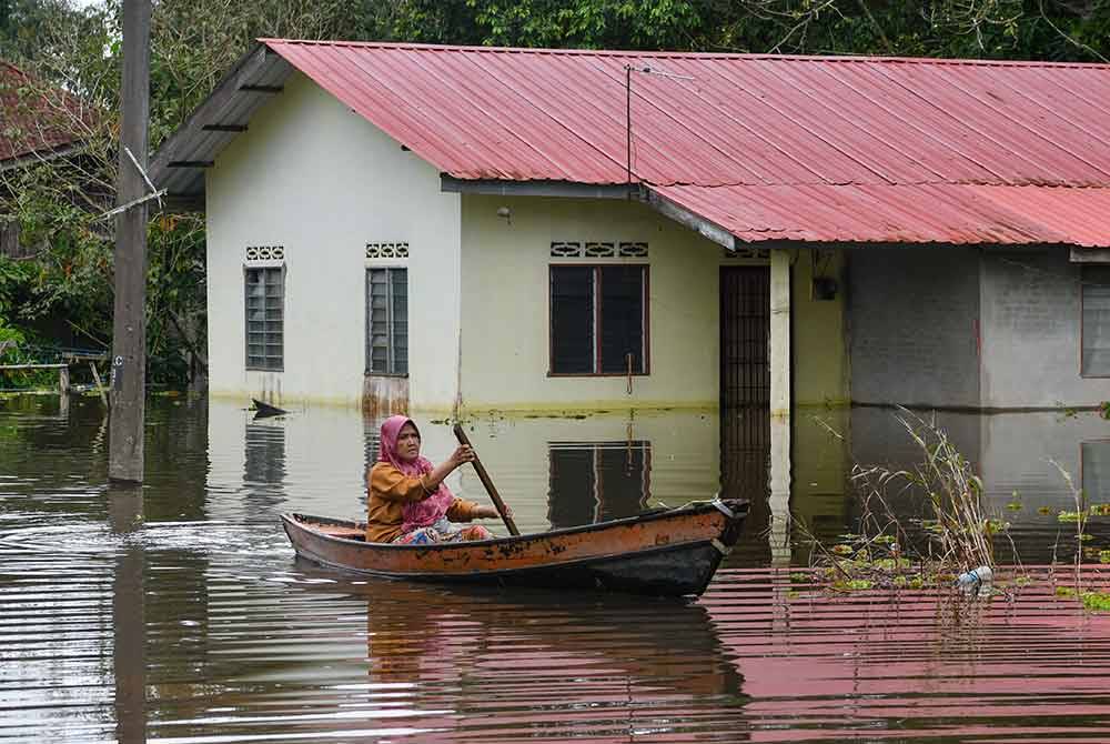 Penduduk, Salehah Mat Daud, 66, menaiki sampan meninjau keadaan rumah yang digenangi air akibat cuaca hujan yang tidak menentu ketika tinjauan di Kampung Pandang Licin, Rantau Panjang pada Ahad lepas. - Foto Bernama