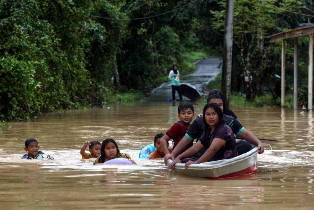 Beberapa kanak-kanak bermain di hadapan kawasan rumah mereka yang masih lagi digenangi air akibat cuaca hujan yang tidak menentu ketika tinjauan di Kampung Kubang Kuau. - Foto Bernama.