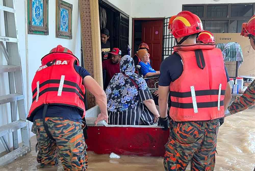 Anggota bomba membantu memindahkan mangsa banjir yang terperangkap di Kampung Mohd Amin, Johor Bahru.