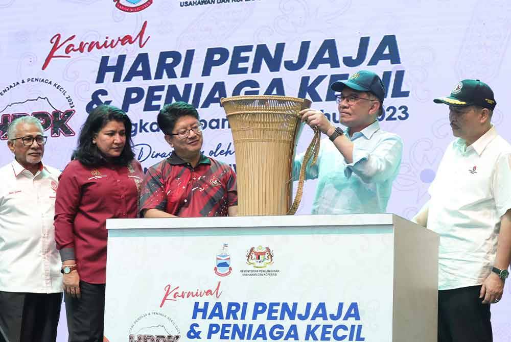 Anwar menyampaikan sijil Anugerah Kecemerlangan Penjaja dan Peniaga Kecil Tahun 2023 kepada salah seorang peserta sempena Karnival Hari Penjaja dan Peniaga Kecil Peringkat Kebangsaan di Dataran Buhavan Square Penampang hari ini. - Foto Bernama