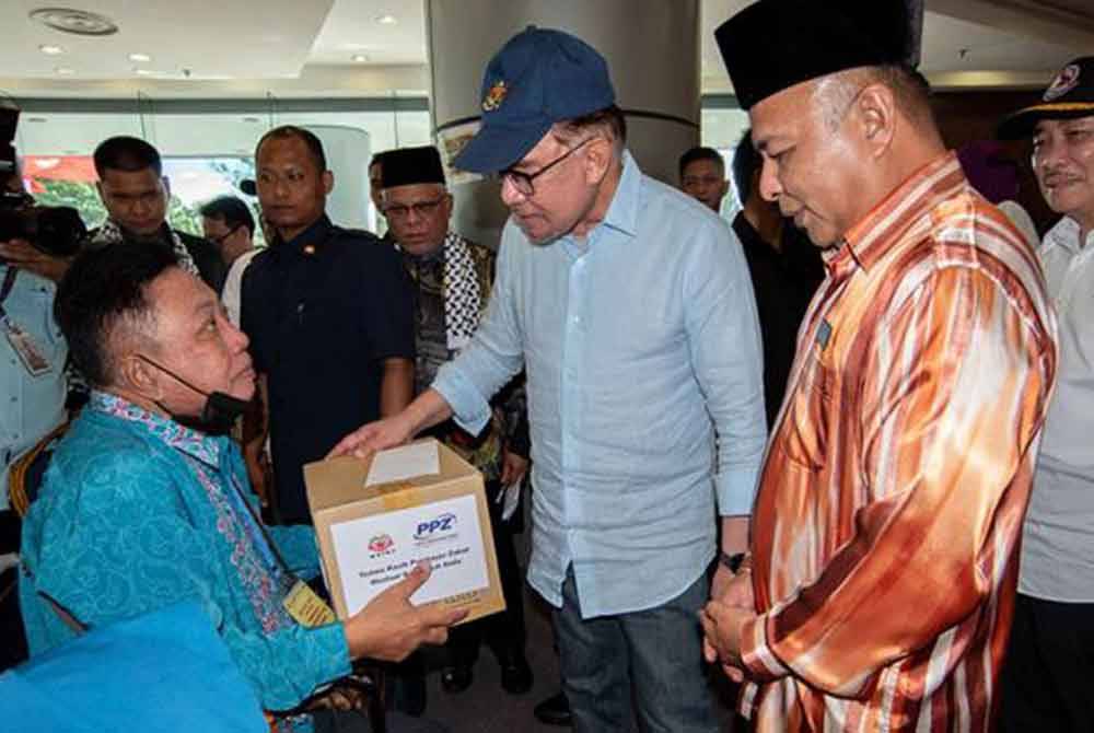 Anwar (tengah) ketika menyempurnakan penyerahan bantuan pada Program Pembasmian Miskin Tegar Wilayah Persekutuan Labuan di Kompleks Ujana Kewangan hari ini. - Gambar Bernama