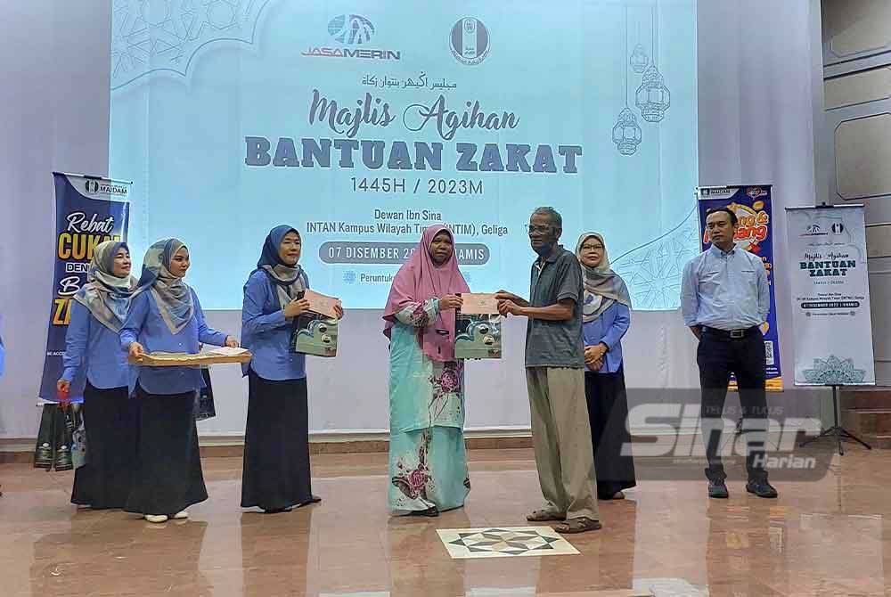 Hamidah (tengah) menyampaikan sumbangan zakat pada salah seorang penerima pada Majlis Agihan Bantuan Zakat di Intan Kampus Wilayah Timur.