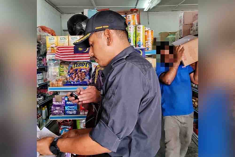 Seorang pekerja kedai mengangkat barang kawalan yang disorokkan