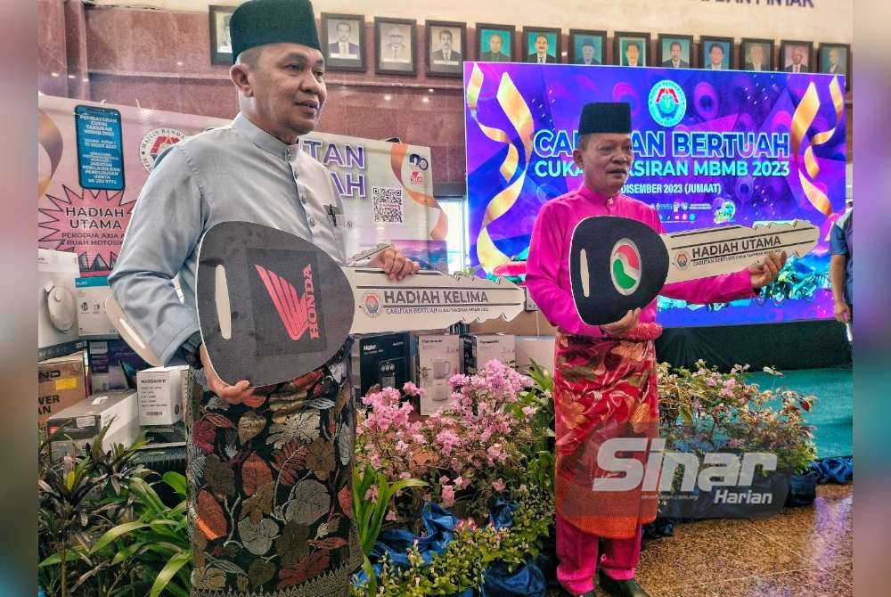 Shadan (kiri) dan Zulkifli (dua dari kiri) menunjukkan hadiah utama yang akan dimenangi pemenang cabutan bertuah di Bangunan MBMB, Ayer Keroh, pada Jumaat.