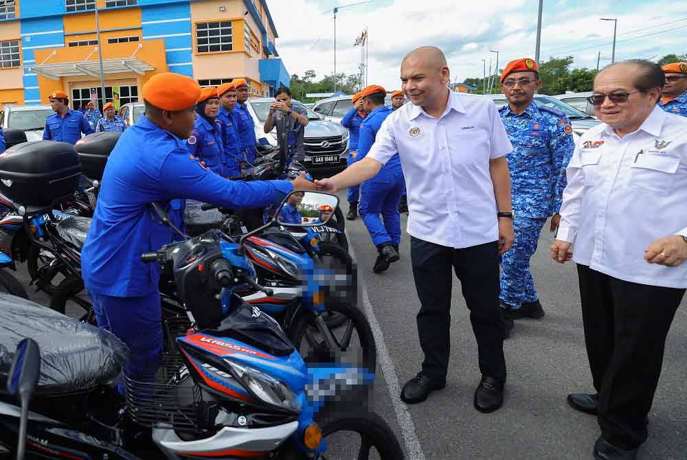 Amar Douglas Uggah Embas (kanan) dan Armizan (dua dari kanan) menyantuni anggota APM Sarawak selepas menyempurnakan penyerahan kenderaan APM Sarawak hari ini. - Foto: Bernama