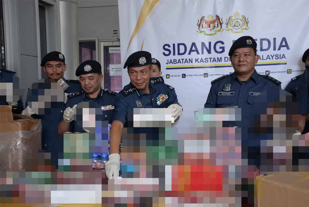 Abdul Ghafar (tengah) menunjukkan rokok dan minuman keras yang dirampas bernilai RM950,000 dalam serbuan di Perak dan Johor, minggu lalu. - Foto: ihsan JKDM