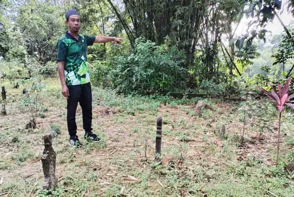 Hanif menunjukkan kawasan tanah perkuburan berdekatan tebing sungai di Kampung Seberang Jertih, Besut yang semakin terhakis setiap kali musim tengkujuh.